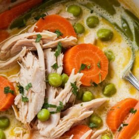 Golden anti inflammatory turmeric chicken soup served in a bowl with fresh coriander leaves.