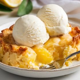 Delicious lemon cobbler garnished with powdered sugar and a slice of fresh lemon.